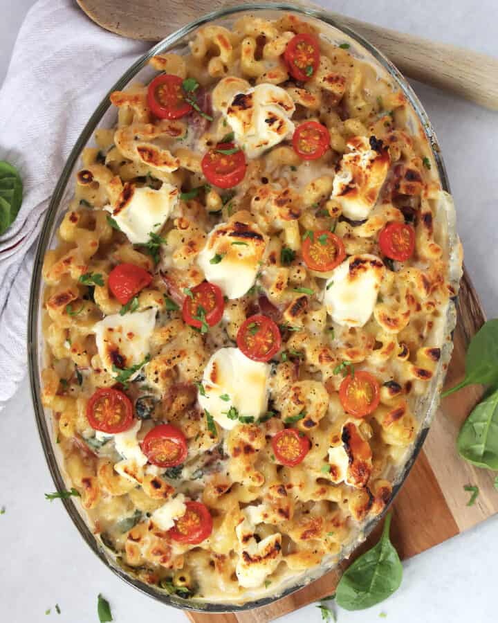 Goat cheese, onion and spinach pasta bake in a glass baking dish.