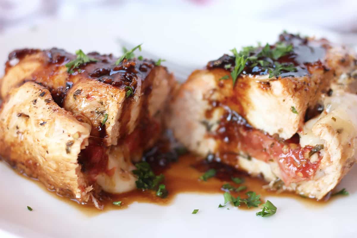 A caprese stuffed chicken breast cut in half and finished with a balsamic reduction.