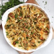 Baked pesto stuffed shells in a creamy sauce, garnished with fresh parsley.