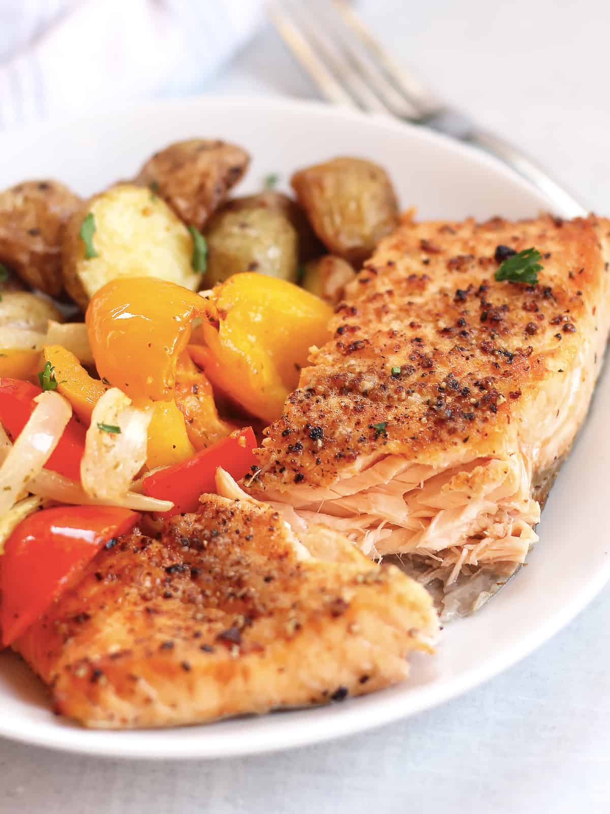 Seasoned salmon, vegetables and potatoes served on a plate.