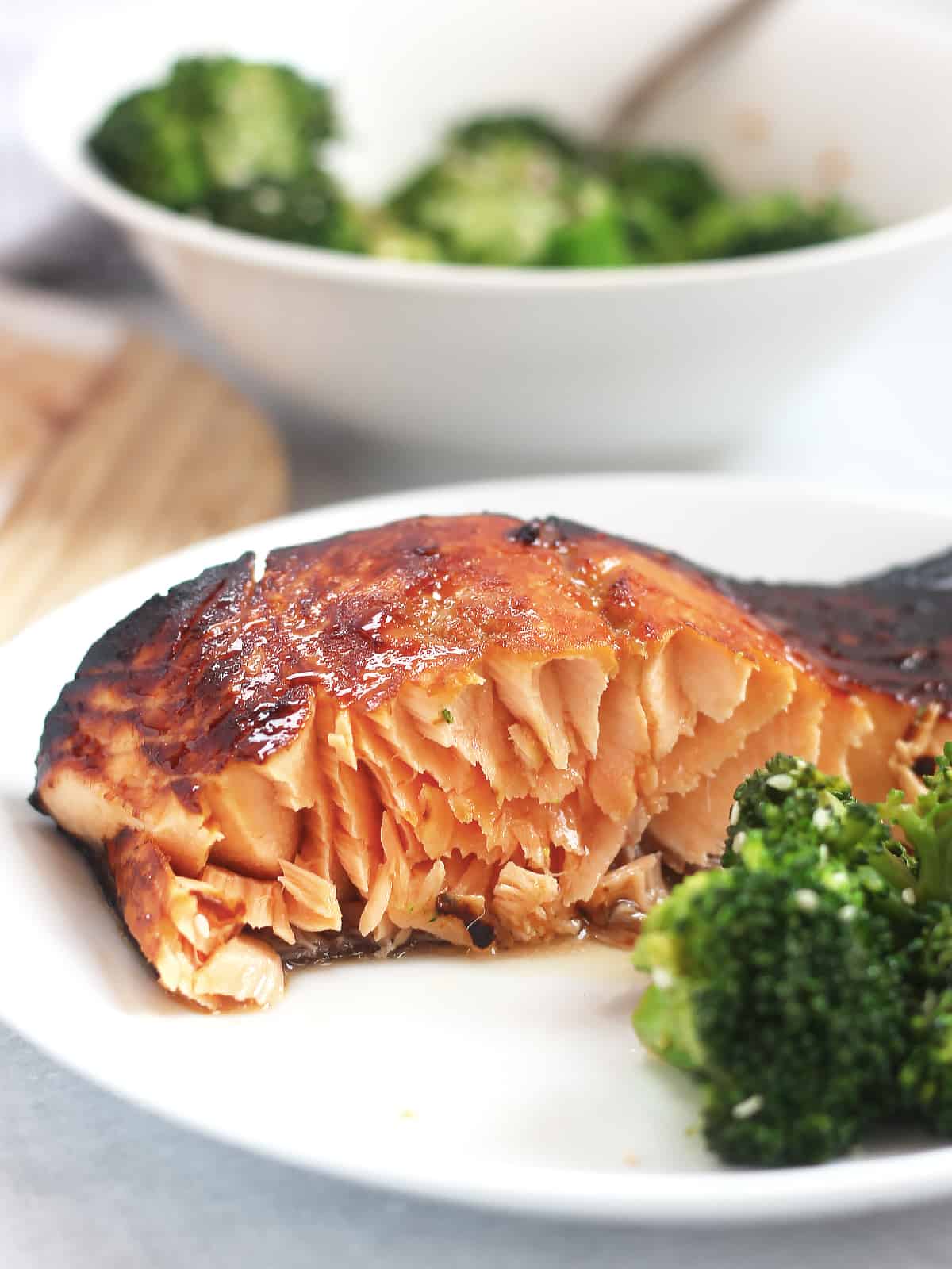 A piece of air fried salmon served on a plate with broccoli.