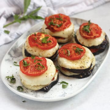 Sliced of eggplant, tomato and mozzarella stacked on top of each other.