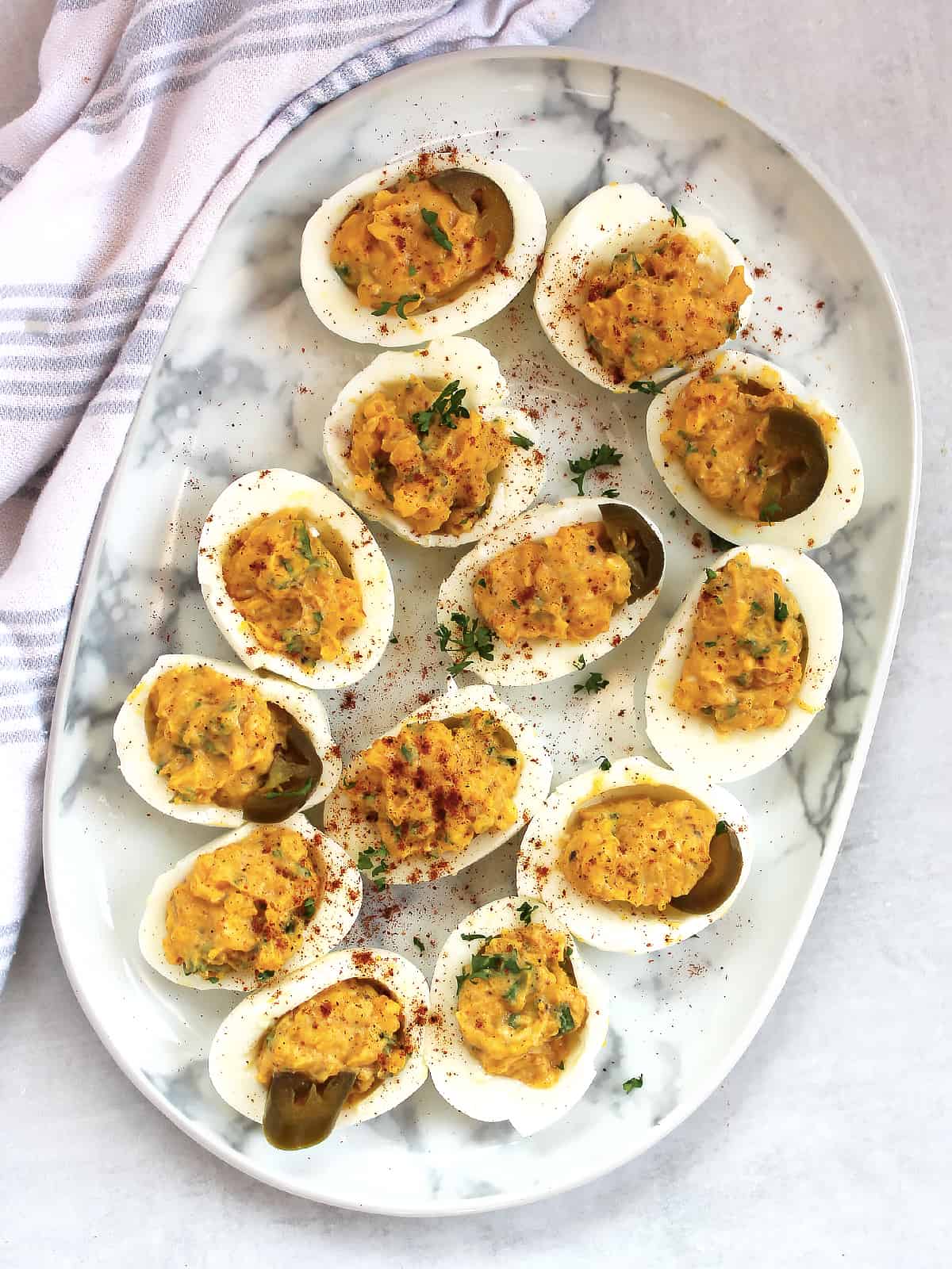 Mexican taco deviled eggs on a serving plate garnished with jalapeno and cilantro.