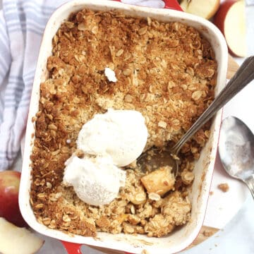Golden brown air fried apple crisp in a baking dish topped with ice cream.