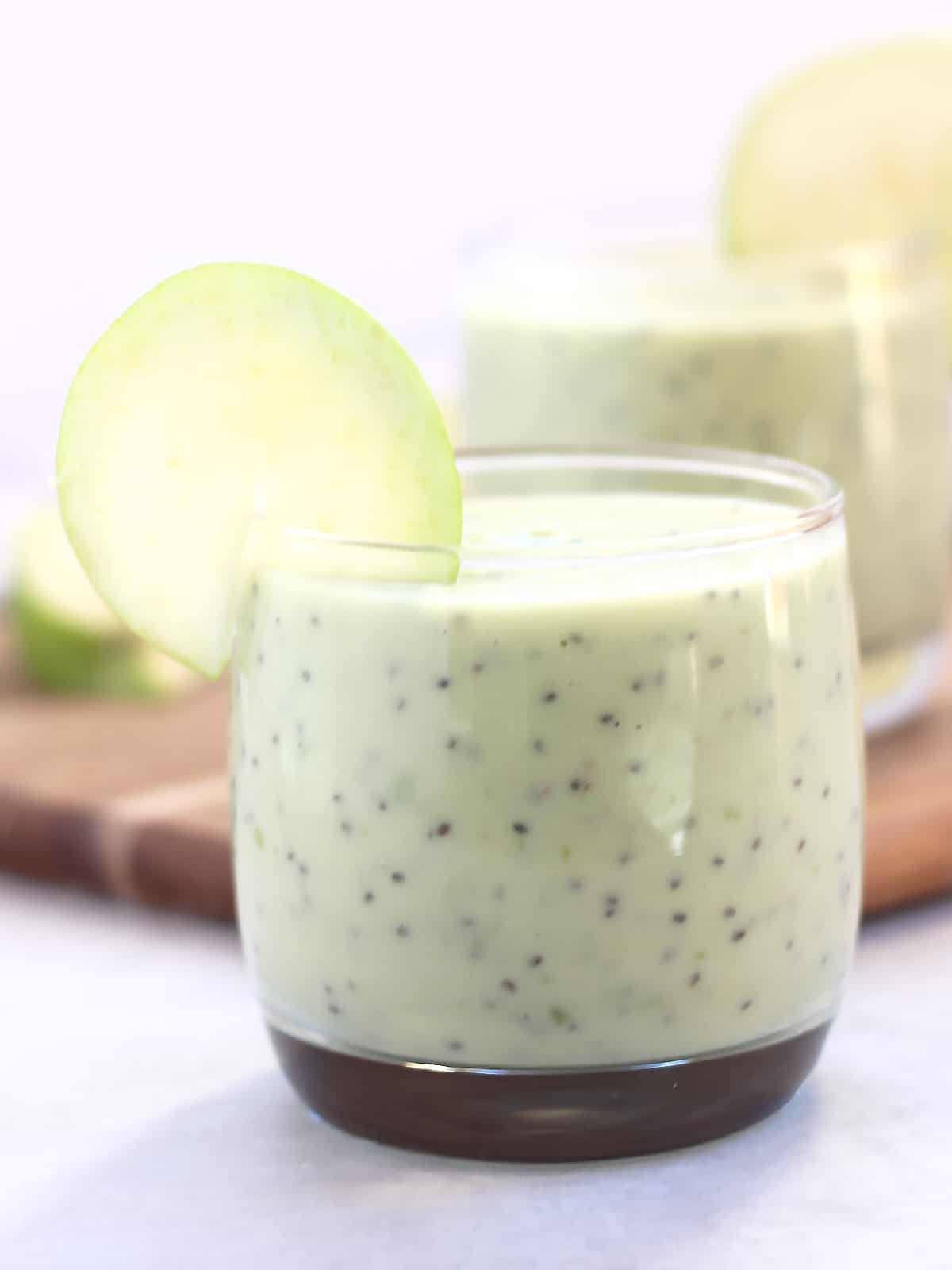 An apple avocado smoothie with chia seeds served in a short glass.