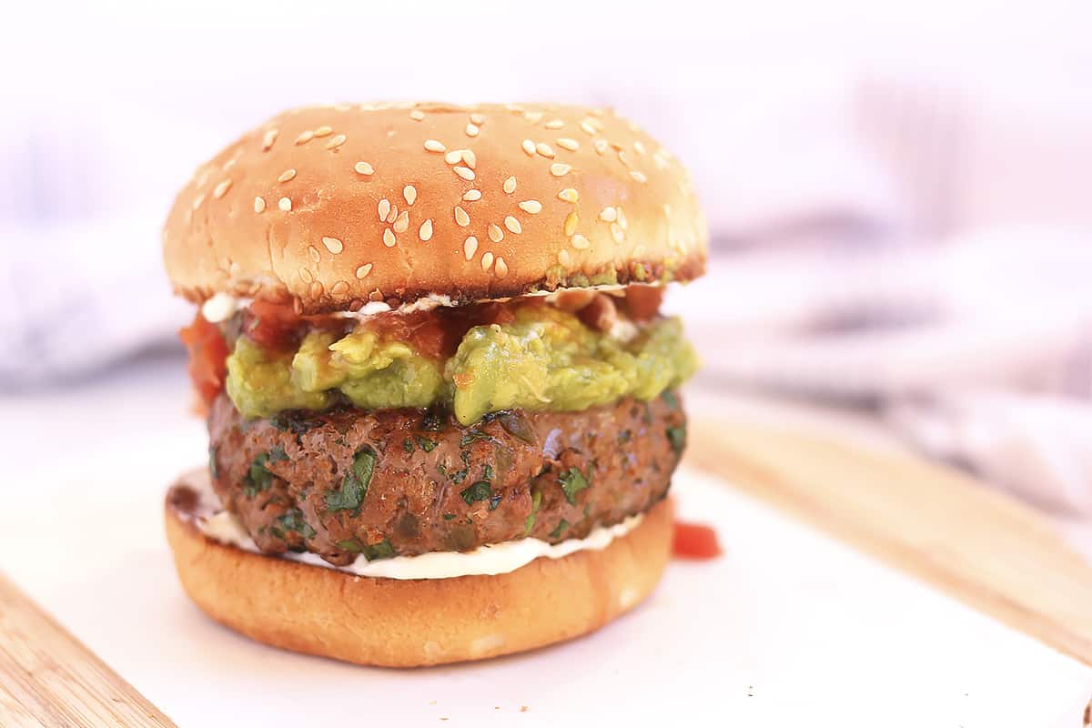 A taco seasoned burger in a bun with toppings.