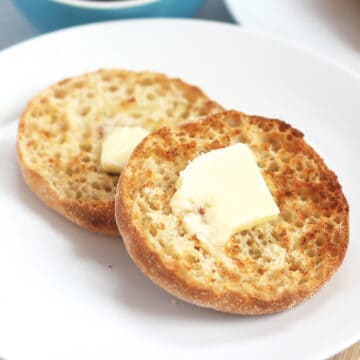 A halved air fried English muffin spread with butter.