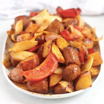 Air fried sausage, bell peppers, onions and potatoes piled up on a serving plate.