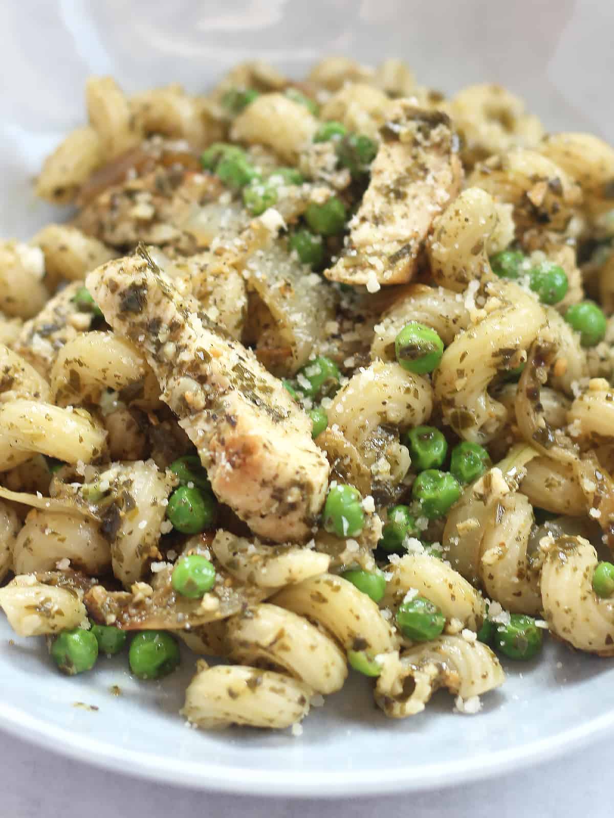 Pieces of cooked chicken breast tossed in pesto pasta.