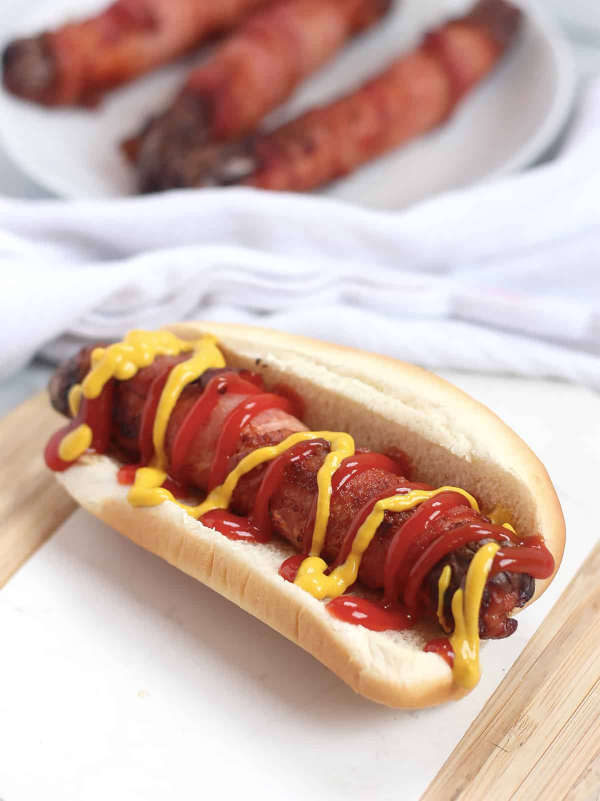 A hot dog in a bun, topped with condiments.