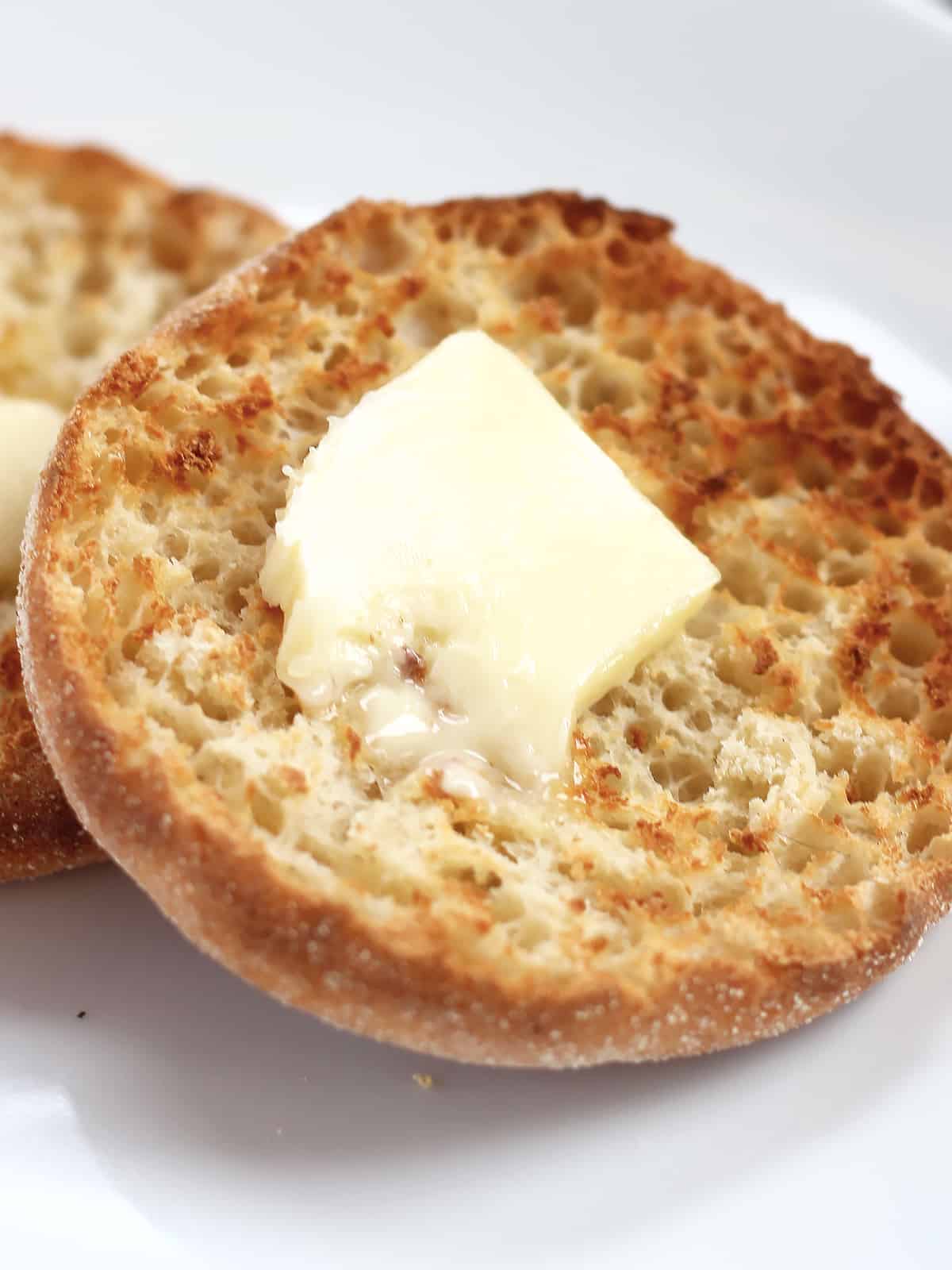 A toasted English muffin half with butter melting on it.
