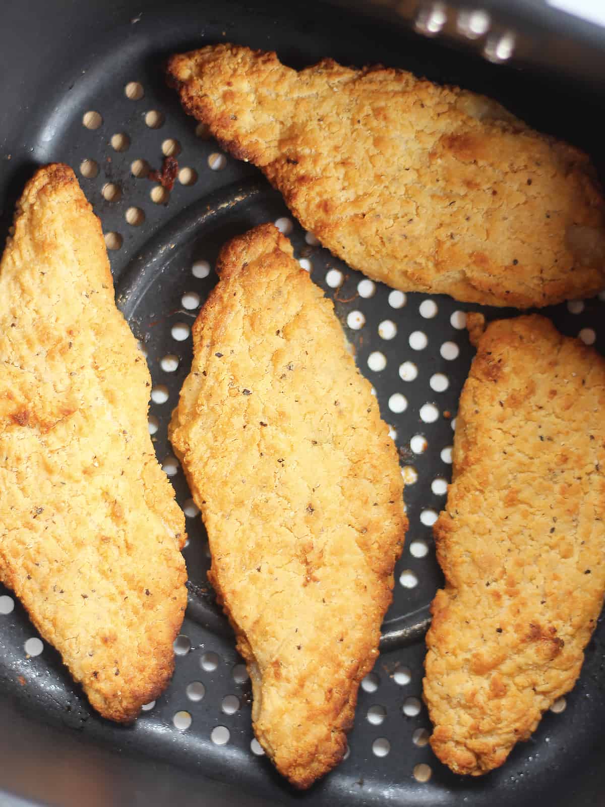 Four pieces of breaded fish cooked in the air fryer basket.