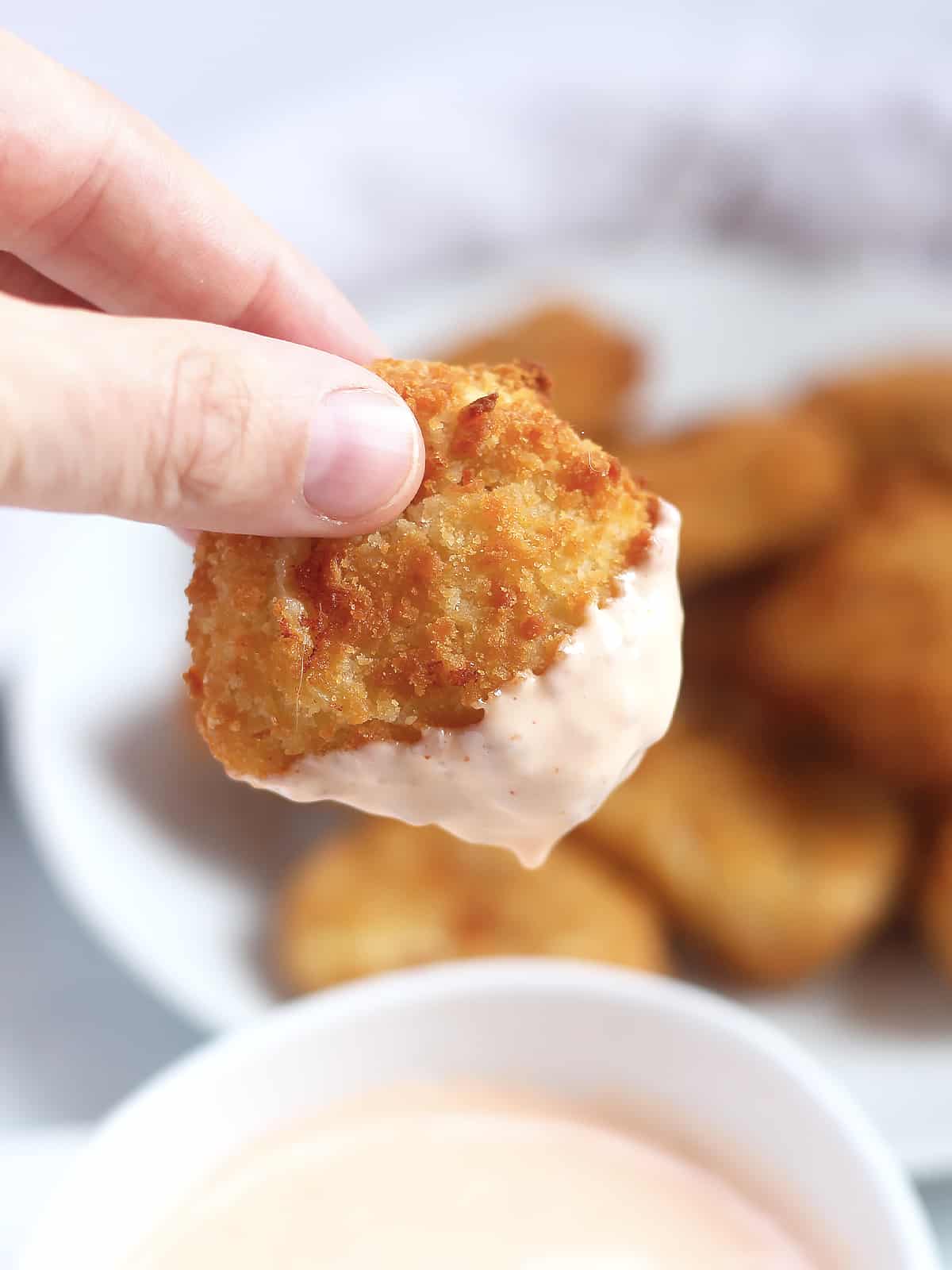 A chicken nugget being dipped in a sauce.