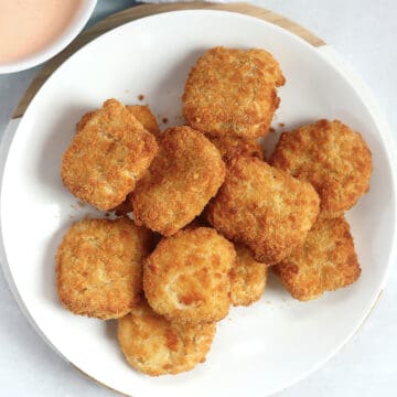 Golden brown air fried chicken nuggets served on a white plate.