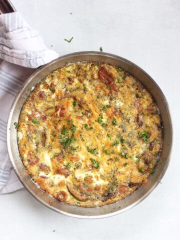 An oven baked bacon frittata in a silver skillet.