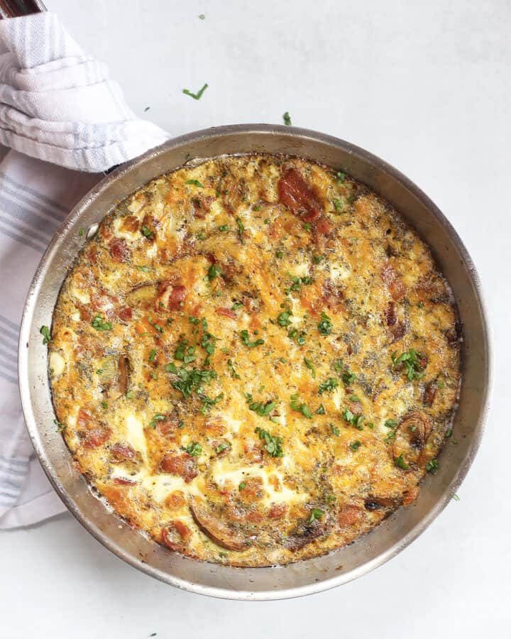 An oven baked bacon frittata in a silver skillet.