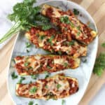 Air fried beef zucchini boats with melted cheese on a serving plate.