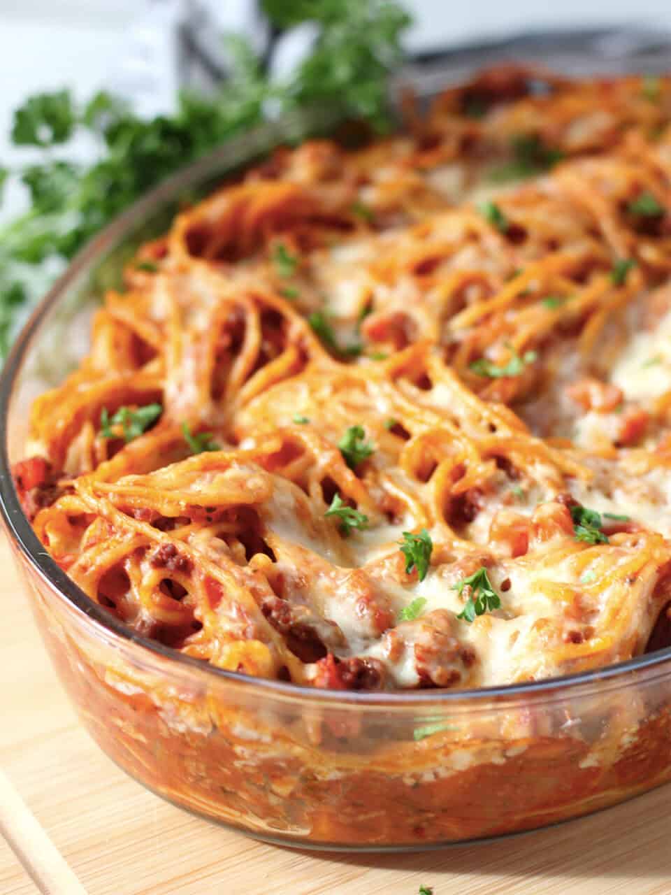 Pasta bake in a casserole dish garnished with fresh parsley.
