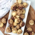 Chocolate and nut dipped petit fours cookies on a white plate.