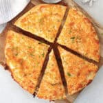 A cheesy garlic bread tortilla garnished with fresh chives.