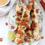 Crispy chicken skewers garnished with red chillies, cilantro and fresh lime.