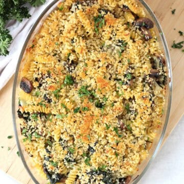 Blue cheese pasta bake with mushrooms and spinach in a glass dish.