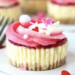 Baked mini cheesecake with pink and white frosting and Valentine's Day sprinkles.