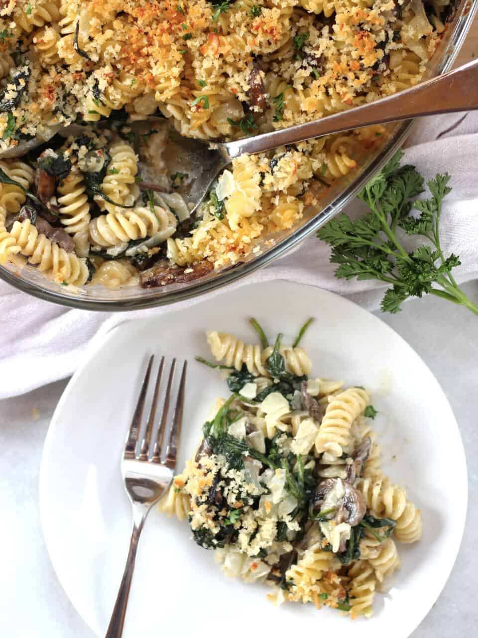 A pasta bake in a glass dish and some served onto a plate.