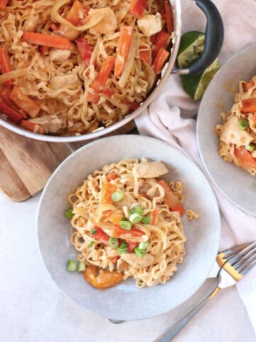 Chicken satay noodles in a large pot with some served into two bowls.