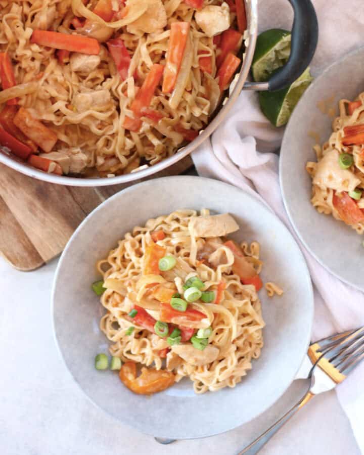 Chicken satay noodles in a large pot with some served into two bowls.