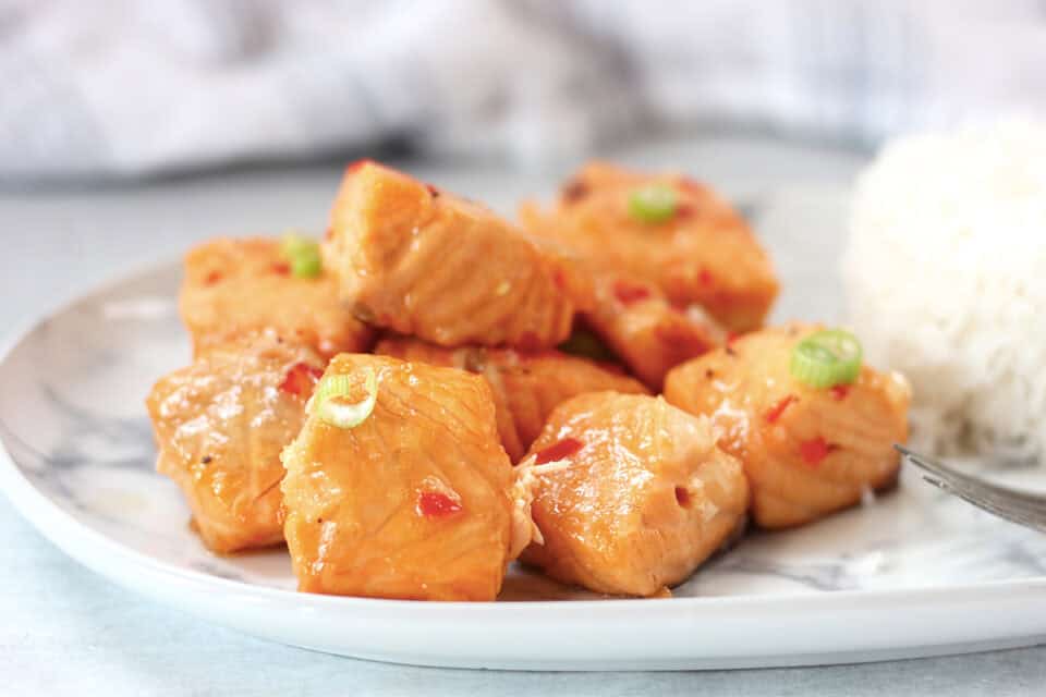 Cubes of cooked salmon garnished with green onion.