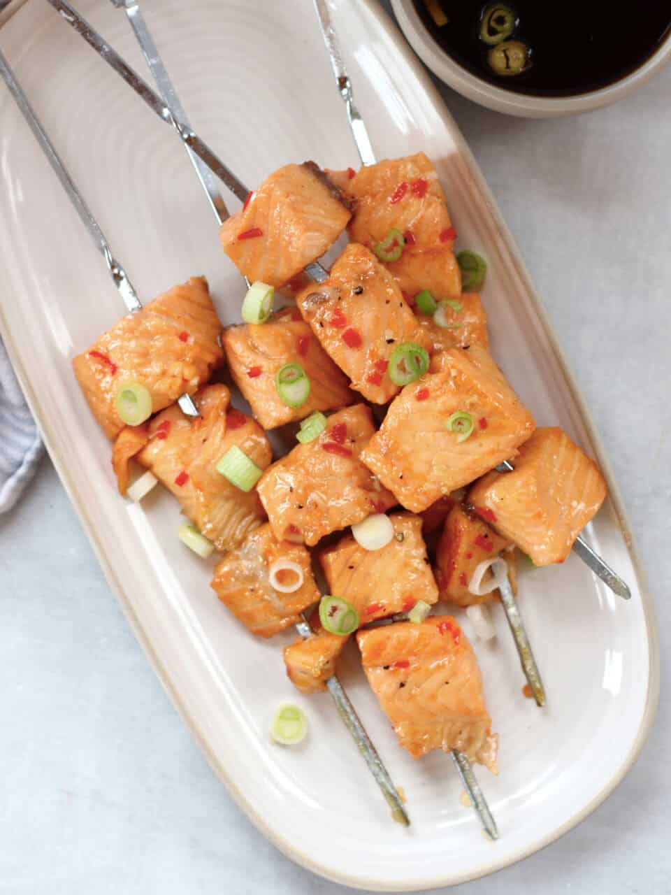 Four salmon skewers served with a soy dipping sauce.