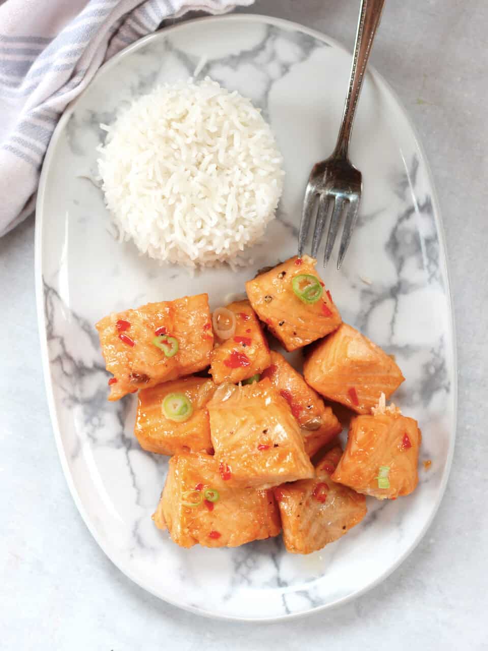 Cubes of cooked salmon served on a plate with rice and a fork.