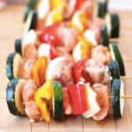 Vegetable and salmon skewers on a wooden cutting board.