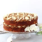 A two layered peach cake on a cake stand decorated with buttercream frosting.