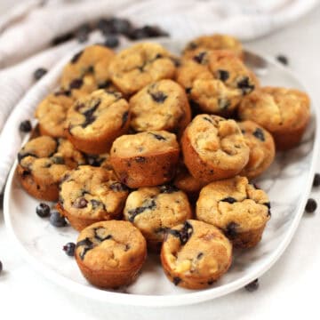 Blueberry mini muffins on a marble plate.