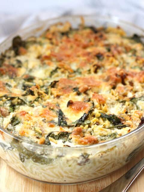 Baked orzo and spinach in a glass baking dish.