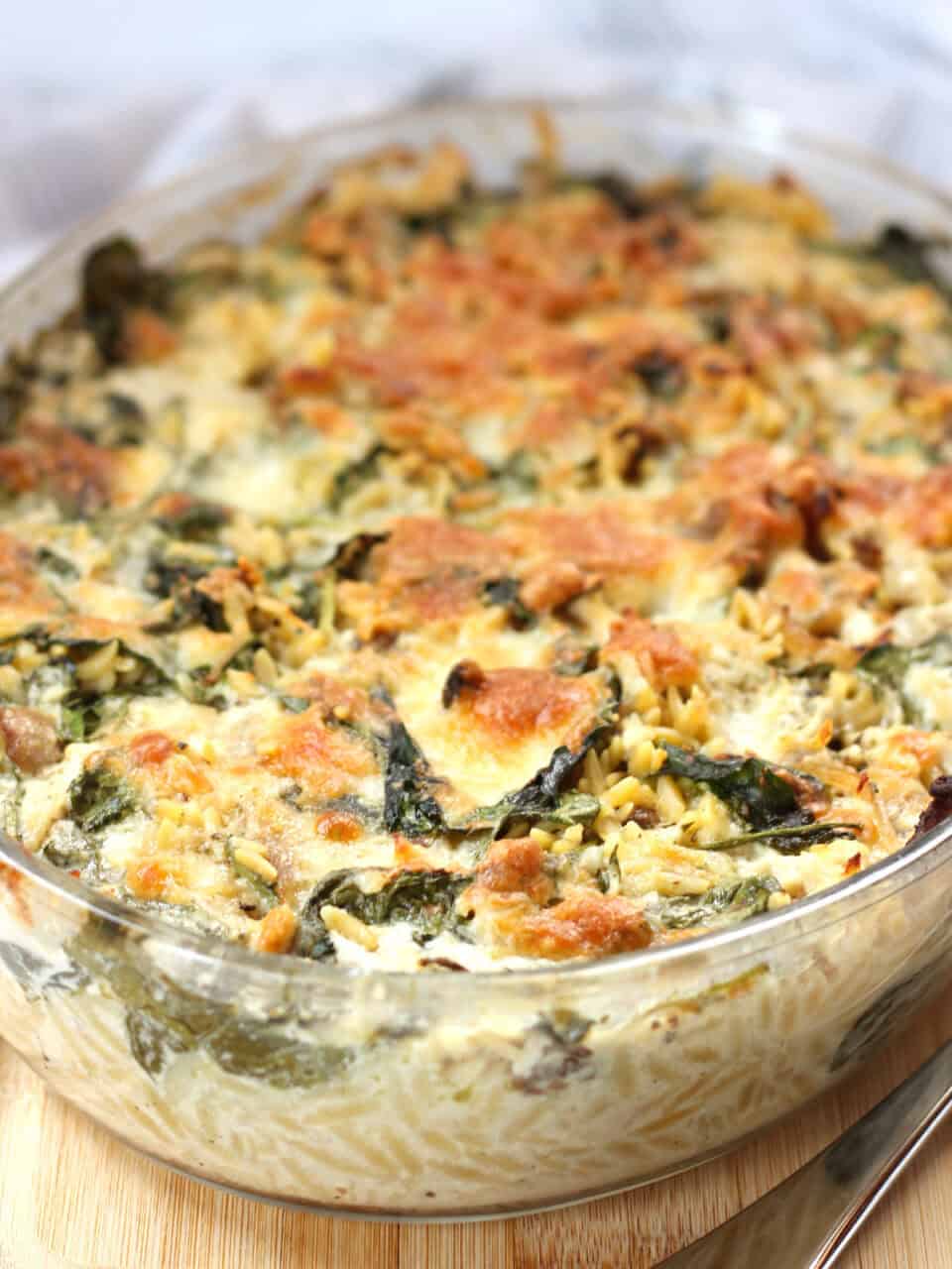 Baked orzo and spinach in a glass baking dish.