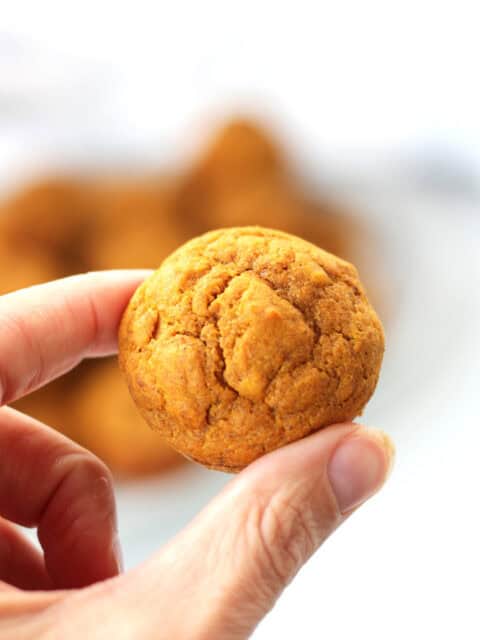 A mini muffin held between a finger and a thumb.