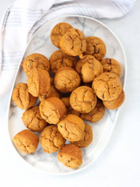 Mini pumpkin muffins served on a white plate.