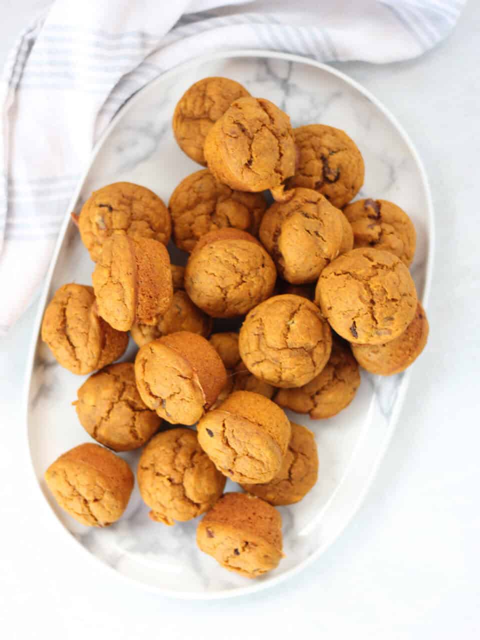 Mini pumpkin muffins served on a white plate.
