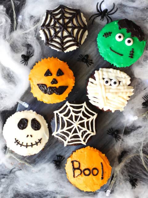 Chocolate cupcakes decorated for Halloween. A skull, spiders web, pumpkin, mummy and Frankenstein.