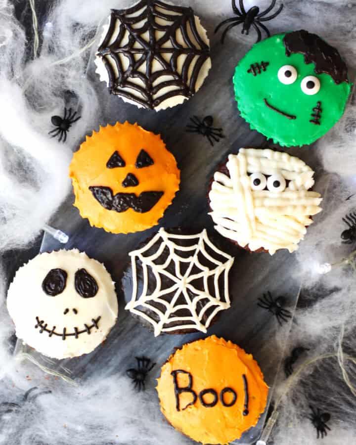Chocolate cupcakes decorated for Halloween. A skull, spiders web, pumpkin, mummy and Frankenstein.
