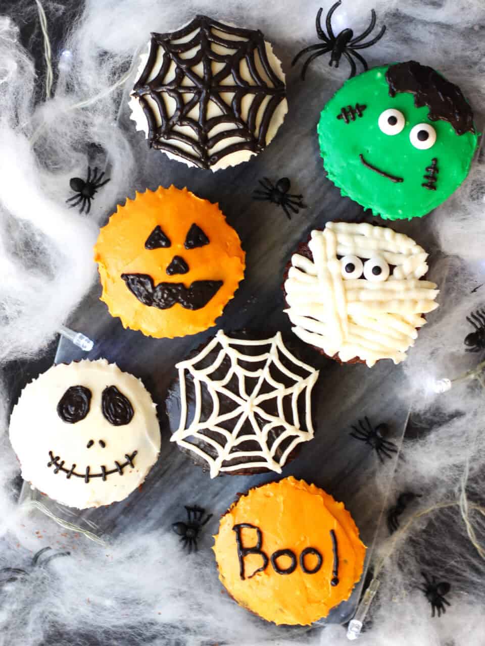 Chocolate cupcakes decorated for Halloween. A skull, spiders web, pumpkin, mummy and Frankenstein.