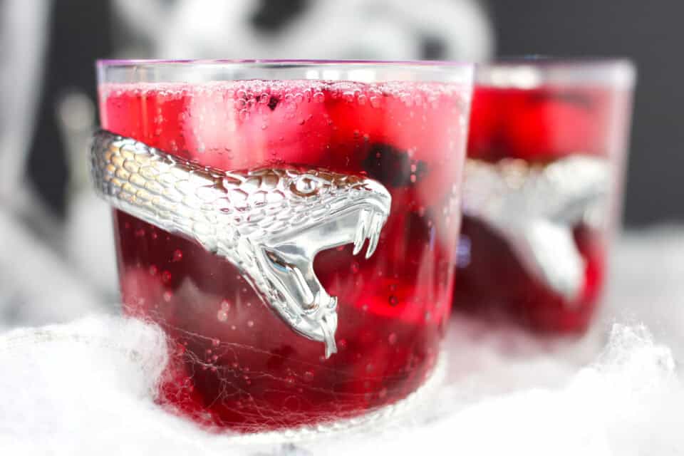 Two glasses of red halloween punch in snake glasses.