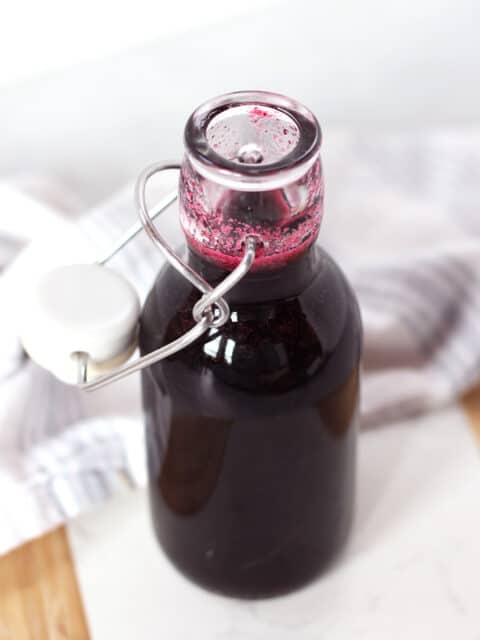 Blueberry simple syrup in a glass bottle.