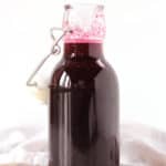 Blueberry simple syrup in a glass bottle with stopper.