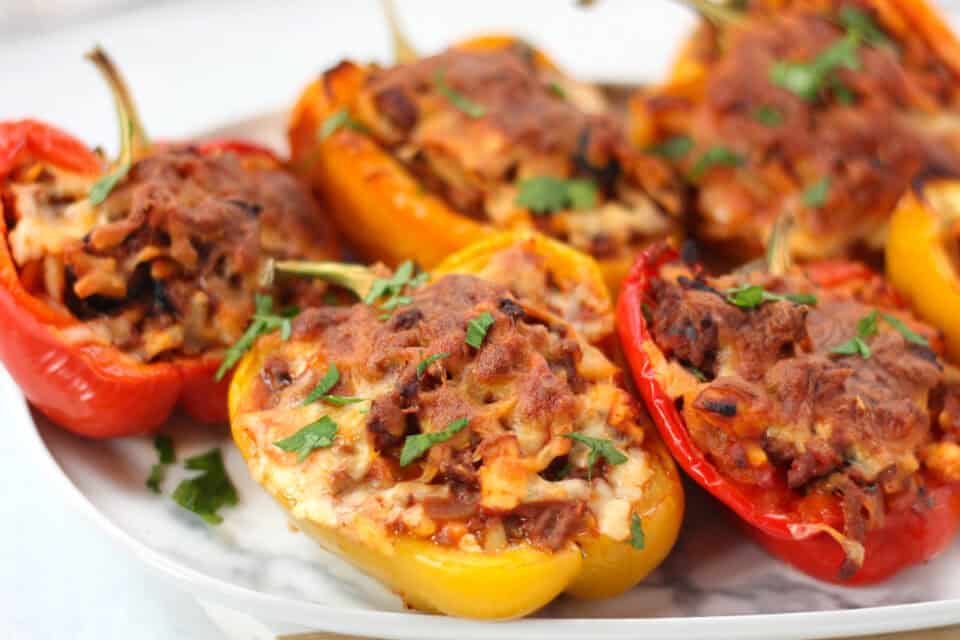 Red, yellow and orange stuffed peppers on a plate.