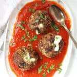 Three cheesy meatballs served with marinara sauce.