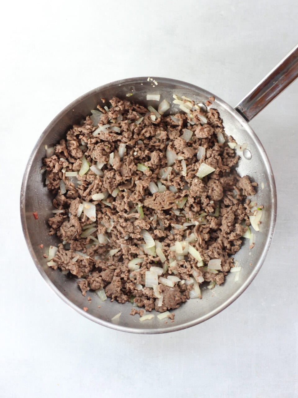 Cooked ground beef and onions in a skillet.